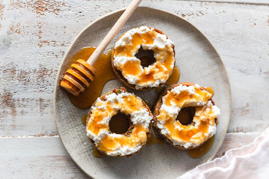 Three bagels on a plate with honey dipper