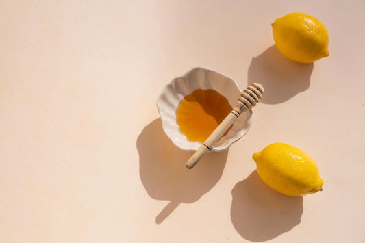 white bowl with honey in it and two lemons